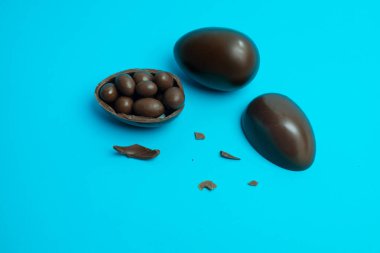 Kırık bir Paskalya yumurtası çikolata kaplı şekerleri parlak mavi bir arka plana döker. Festival, tatlı ve şekerleme temalı görseller için mükemmel..