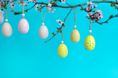 Çiçek açan bir ağaç dalına pastel sarısı ve pembeyle süslenmiş Paskalya yumurtaları asmak. Paskalya, bahar ve mevsimsel kutlamaların taze ve şenlikli bir temsili..