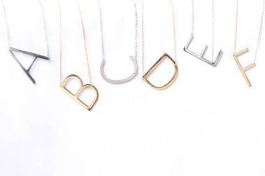 Gümüş ve altından yapılmış minimalist harf kolyeleri. Benzersiz eğimli bir tasarımı var. Özelleştirilmiş moda, takılar, zarif isim aksesuarları.