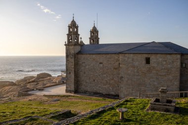 İspanya 'nın Muxa kentindeki A Virxe da Barca' nın mabedi dramatik Atlantik uçurumlarına tünedi. Camino de Santiago 'da önemli bir durak. Gün batımı.