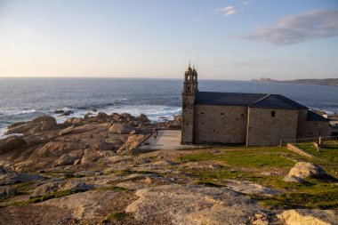 İspanya 'nın Muxa kentindeki A Virxe da Barca' nın mabedi dramatik Atlantik uçurumlarına tünedi. Camino de Santiago 'da önemli bir durak. Gün batımı.
