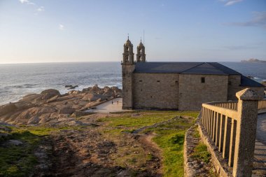 İspanya 'nın Muxa kentindeki A Virxe da Barca' nın mabedi dramatik Atlantik uçurumlarına tünedi. Camino de Santiago 'da önemli bir durak. Gün batımı.