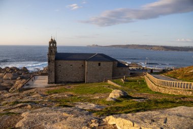 İspanya 'nın Muxa kentindeki A Virxe da Barca' nın mabedi dramatik Atlantik uçurumlarına tünedi. Camino de Santiago 'da önemli bir durak. Gün batımı.