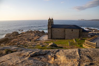 İspanya 'nın Muxa kentindeki A Virxe da Barca' nın mabedi dramatik Atlantik uçurumlarına tünedi. Camino de Santiago 'da önemli bir durak. Gün batımı.