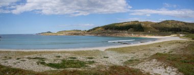 Praia de Lourido 'daki Atlantik kıyıları, Muxa, Galiçya, İspanya. Yumuşak kumullar, sakin deniz ve kıyıya giden yeşil bir patika içeren panoramik sahil manzarası.