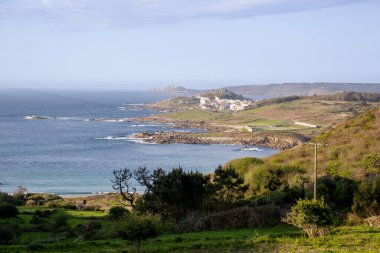 Praia de Lourido 'daki Atlantik kıyıları, Muxa, Galiçya, İspanya. Yumuşak kumullar, sakin deniz ve kıyıya giden yeşil bir patika içeren panoramik sahil manzarası.