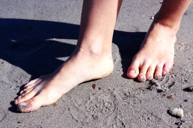 Işıklı kadın bacakları ve kumsalda gölge.