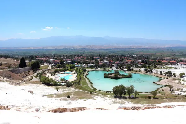 Büyüleyici bir doğa harikası, beyaz teraslar çağlayarak aşağı iniyor, berrak mavi gökyüzünün altında akan su ve mineral yataklarının nefes kesici bir sahnesini oluşturuyor.