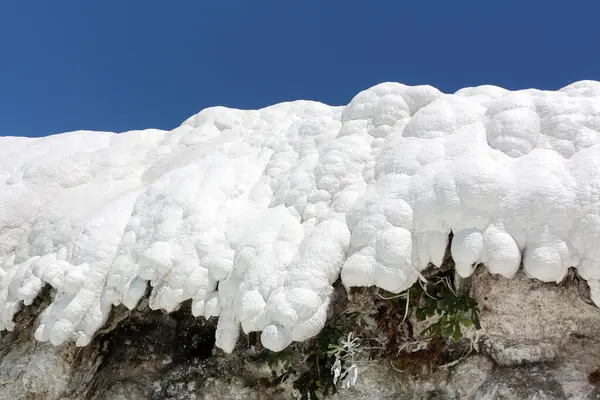 Büyüleyici bir doğa harikası, beyaz teraslar çağlayarak aşağı iniyor, berrak mavi gökyüzünün altında akan su ve mineral yataklarının nefes kesici bir sahnesini oluşturuyor.