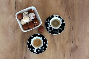 İki fincan espresso ahşap bir masada çeşitli mantarlarla dolu kare bir kasenin yanında, cezbedici bir ziyafet yaratıyor.