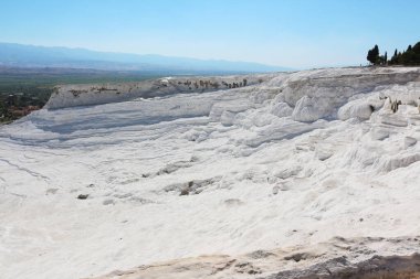 Pamukkale 'nin nefes kesen beyaz terasları, berrak mavi gökyüzünün altında kayarak eşsiz ve nefes kesici bir doğal manzara yaratıyor..