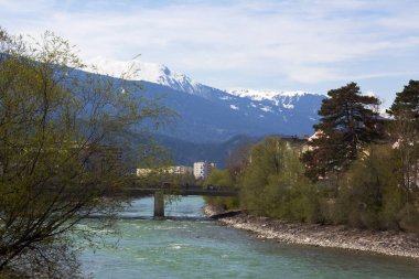 Innsbruck şehri, görkemli karla kaplı Alpler tarafından çerçevelenmiş, akmakta olan Inn Nehri 'nin yanında yer almaktadır. Parçalı bulutlu gökyüzünün altında, güzel bir kentsel doğa karışımı sergilenmektedir.