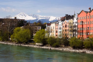 Bu, Innsbruck, Avusturya 'nın manzarası, Inn Nehri' ni çevreleyen ikonik renkli binaları, karla kaplı Nordkette dağlarının çarpıcı zemininde yer alıyor.