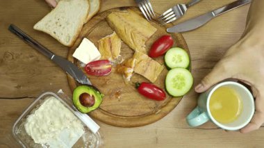 Dilimlenmiş somon, taze sebze, ekmek ve kırsal bir ahşap masada sıcak bir içeceğin tadını çıkarın. Güne enerji dolu başlamak için mükemmel..