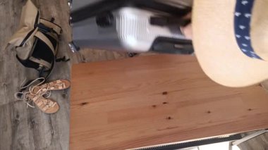 Bir insan, rahat bir ayakkabı ve sırt çantasıyla çevrili sağlam ahşap bir yüzeye bavul yerleştirir. Bu da gün ışığında bir seyahat macerası yaşandığını gösterir..