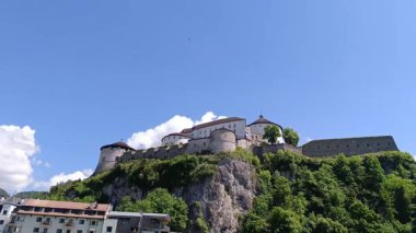 Avusturya 'daki Kufstein kalesinin güzelliğini deneyimleyin. Bulutlar gökyüzünde sürüklenirken, yamaçtan çarpıcı mimari ve çarpıcı manzaraları gözler önüne seriyor..