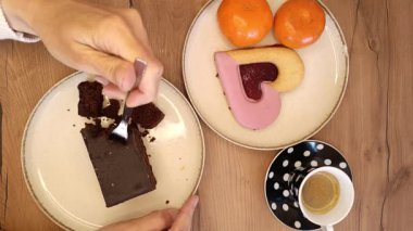 Sıcak bir tatlı anın tadını çıkarın. Bir dilim zengin çikolatalı pasta, canlı kalp şeklinde kurabiye ve rahatlatıcı bir atmosferde bir fincan espresso eşliğinde taze mandalinalar..