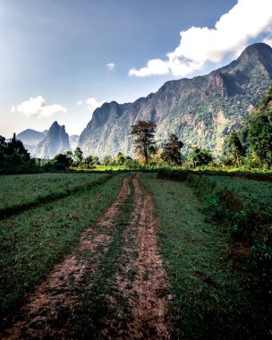 Vang Vieng 'in kırsal kesimindeki Laos' ta sabah erken saatlerde kireçtaşı dağlarının vurduğu güzel manzaraya giden toprak yol..