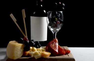 Koyu arkaplanda peynir, üzüm, şarap ve salam olan zarif şarküteri tahtası. Yüksek kalite fotoğraf