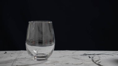 Mermer zemin üzerinde boş şeffaf şarap kadehi koyu arkaplan, minimalist konsept. Yüksek kalite fotoğraf