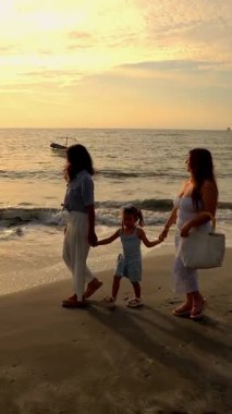  Lezbiyen çift gün batımında kızlarıyla sahilde yürüyor. Yüksek kalite 4k görüntü
