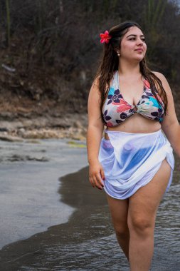 Ayrıca bulutlu bir günde sahilde yürüyen ve ufka bakan cüsseli bir kadın. Yüksek kalite fotoğraf