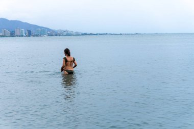 Bulutlu bir günde yüzmek için denize giren Latin bir kadın. Yüksek kalite fotoğraf