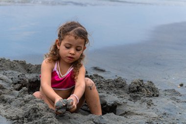Plajda kumla oynayan pembe mayolu Latin kız. Yüksek kalite fotoğraf