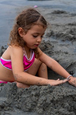 Plajda kumla oynayan pembe mayolu Latin kız. Yüksek kalite fotoğraf