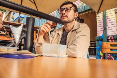 Beyaz tenli Latin bir adam gün batımında Bogota 'da bir koloni caddesinde öğle yemeğini yiyor. Konsepti tüketiyorum. Yüksek kalite fotoğraf