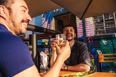 Mutlu ve gülümseyen Latin arkadaşlar kutlama ve yaşam tarzı konsepti için gün batımında sömürge caddesinde bira içiyorlar. Yüksek kalite fotoğraf