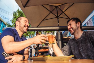 Mutlu ve gülümseyen Latin arkadaşlar kutlama ve yaşam tarzı konsepti için gün batımında sömürge caddesinde bira içiyorlar. Yüksek kalite fotoğraf