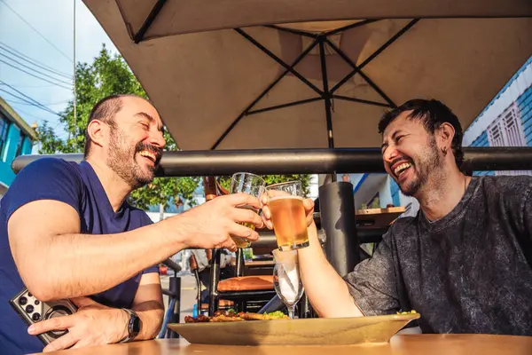 Mutlu ve gülümseyen Latin arkadaşlar kutlama ve yaşam tarzı konsepti için gün batımında sömürge caddesinde bira içiyorlar. Yüksek kalite fotoğraf