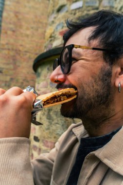 Tipik Kolombiya tatlısı Oblea yiyen Latin bir adam öğle vakti Bogota sokaklarında içki içiyor. Sokak yemekleri, dışarıda yemek ve turizm kavramı. Yüksek kalite fotoğraf