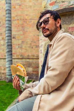 Tipik Kolombiya tatlısı Oblea yiyen Latin bir adam öğle vakti Bogota sokaklarında içki içiyor. Sokak yemekleri, dışarıda yemek ve turizm kavramı. Yüksek kalite fotoğraf