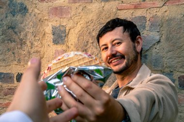 Dışarıda bir Oblea paylaşan Latin bir adam, tipik bir Kolombiya sokak tatlısı, dışarıda yemek konsepti için. Yüksek kalite fotoğraf