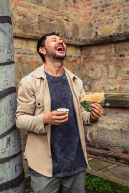 Latin bir adam öğle vakti Bogota sokaklarında, tipik bir Kolombiya tatlısı olan Oblea 'yı içerek gülüyor ve yiyor. Sokak yemekleri, dışarıda yemek ve turizm kavramı. Yüksek kalite fotoğraf