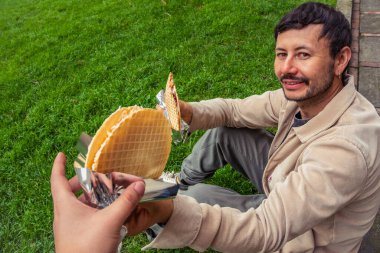 Dışarıda bir Oblea paylaşan Latin bir adam, tipik bir Kolombiya sokak tatlısı, dışarıda yemek konsepti için. Yüksek kalite fotoğraf