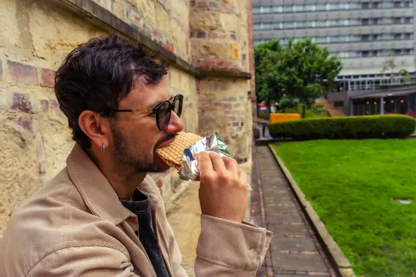 Tipik Kolombiya tatlısı Oblea yiyen Latin bir adam öğle vakti Bogota sokaklarında içki içiyor. Sokak yemekleri, dışarıda yemek ve turizm kavramı. Yüksek kalite fotoğraf