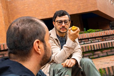 Bir grup adam bir araya geldi, merdivenlerde şeftali yerken konuşup gülüyorlardı. Şeftali ayı, sağlıklı yiyecekler, refah, arkadaşlık ve çiftler konsepti budur. Yüksek kalite fotoğraf