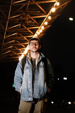 Gece hayatı konsepti için canlı sarı ışıkları olan Bogota şehrinde yalnız poz veren genç bir adam. Yüksek kalite fotoğraf