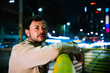 Tek başına genç bir adam gece hayatı konsepti için canlı renkli ışıkları olan Bogota şehrinin canlı gece hayatını izliyor. Yüksek kalite fotoğraf