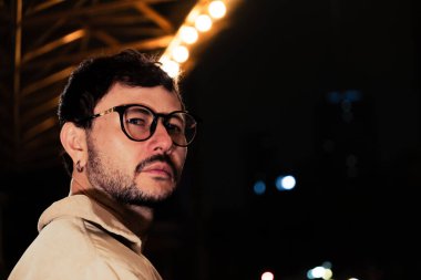 Gece hayatı konsepti için canlı sarı ışıkları olan Bogota şehrinde yalnız poz veren genç bir adam. Yüksek kalite fotoğraf