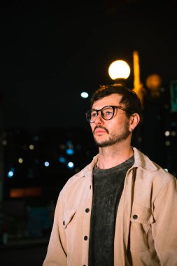 Gece hayatı ve moda anlayışı için renkli ışıkları olan Bogota şehrinde yalnız poz veren genç bir adam. Yüksek kalite fotoğraf