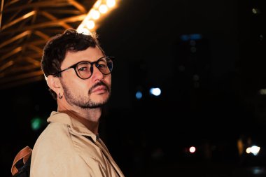 Gece hayatı konsepti için canlı sarı ışıkları olan Bogota şehrinde yalnız poz veren genç bir adam. Yüksek kalite fotoğraf