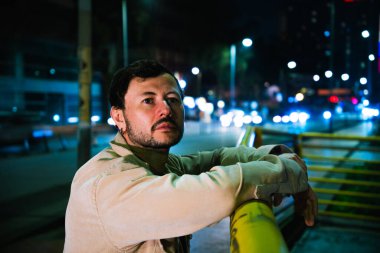 Tek başına genç bir adam gece hayatı konsepti için canlı renkli ışıkları olan Bogota şehrinin canlı gece hayatını izliyor. Yüksek kalite fotoğraf