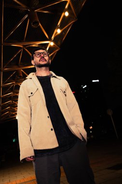 Gece hayatı konsepti için canlı sarı ışıkları olan Bogota şehrinde yalnız poz veren genç bir adam. Yüksek kalite fotoğraf