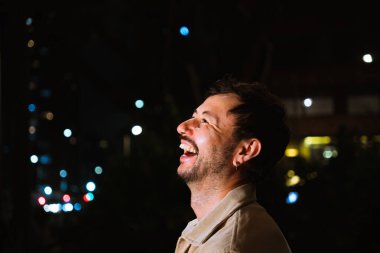 Genç bir adam yalnız gülüyor ve gece hayatı konsepti için renkli ışıkları olan Bogota şehrinin canlı gece hayatını izliyor. Yüksek kalite fotoğraf