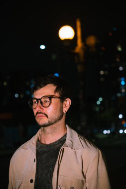 Gece hayatı ve moda anlayışı için renkli ışıkları olan Bogota şehrinde yalnız poz veren genç bir adam. Yüksek kalite fotoğraf