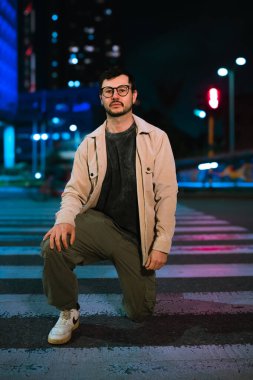 Gece hayatı ve moda anlayışı için renkli ışıkları olan Bogota şehrinde yalnız poz veren genç bir adam. Yüksek kalite fotoğraf